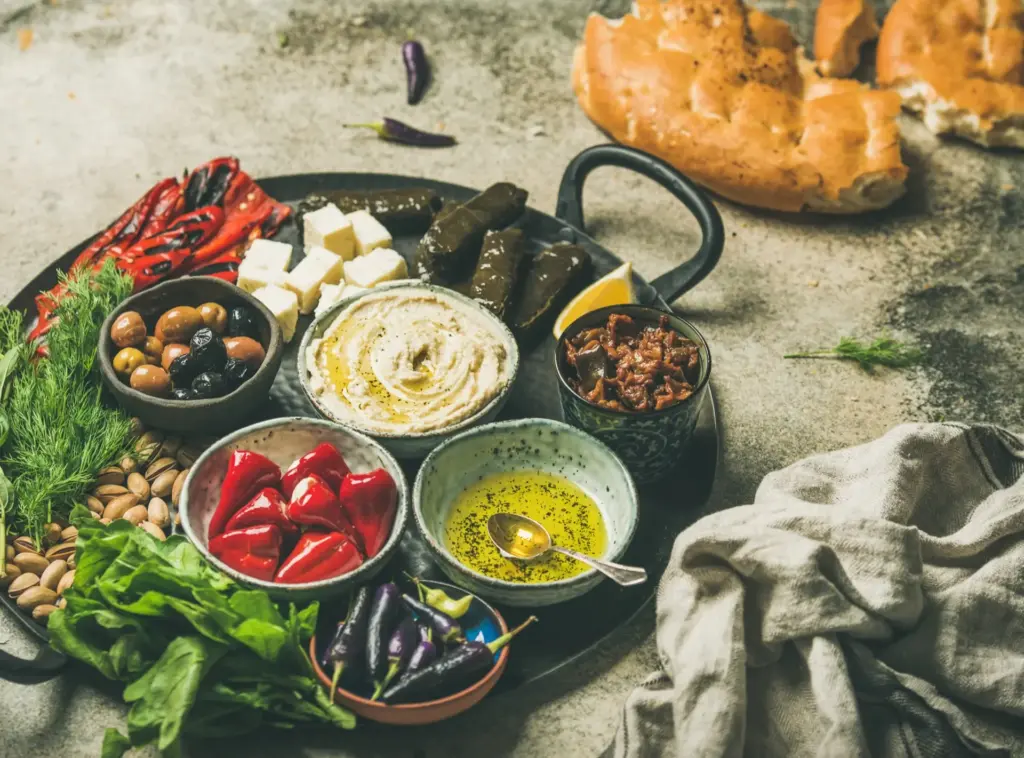 Mediterranes veganes Catering: Buntes Arrangement aus cremigem Hummus, Oliven, Pistazien und gefüllten Minipaprika von NAR Kitchen