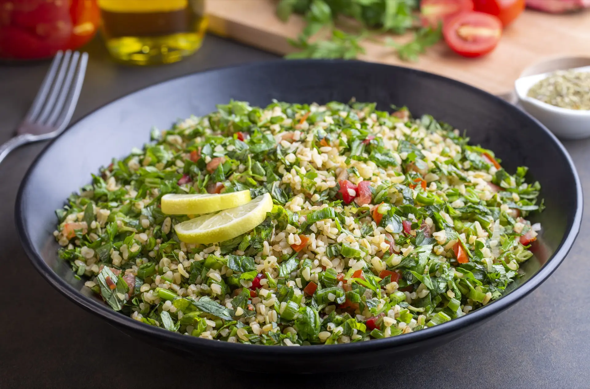 Frischer Tabbouleh-Salat: Ein traditioneller Petersiliensalat mit Bulgur, gewürfelten Tomaten und Zitronengarnitur in einer schwarzen Schale