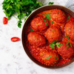 Pflanzliches Event-Catering: Herzhafte Linsenbällchen in Kokos-Curry-Sauce als warmes Hauptgericht von NAR Kitchen