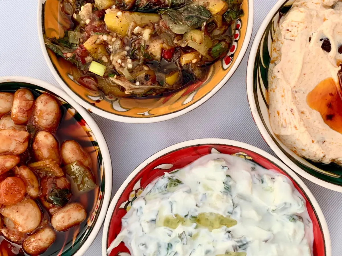 Mediterranes veganes Catering: Buntes Arrangement aus cremigem Hummus, Oliven, Pistazien und gefüllten Minipaprika von NAR Kitchen